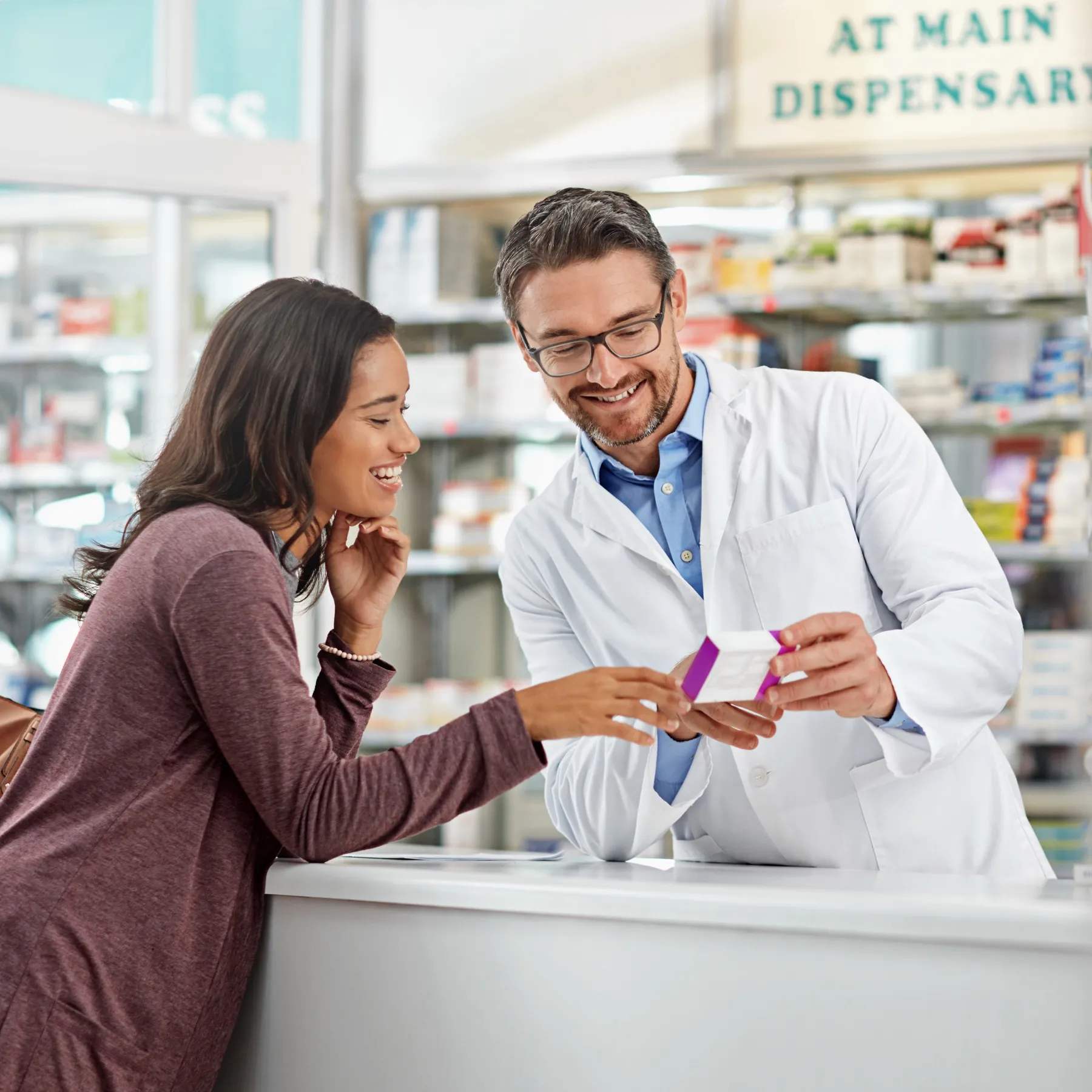 A pharmacist explains a medication to a customer at the pharmacy counter